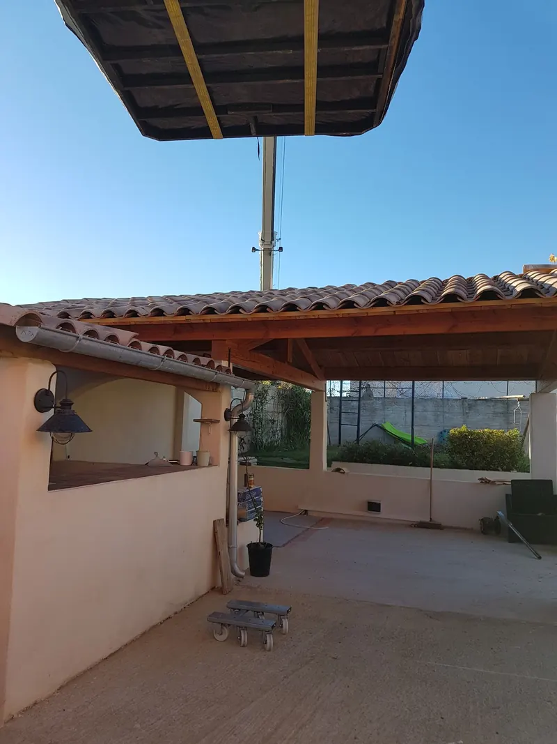 Spa emballé suspendu à la grue au-dessus du toit de tuiles d'une pergola à Cazouls-lès-Béziers