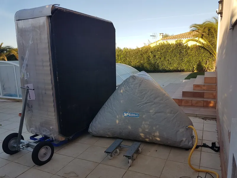 Spa emballé debout sur un chariot à côté d'un coussin gonflable, sur une terrasse près d'une piscine à Caveirac