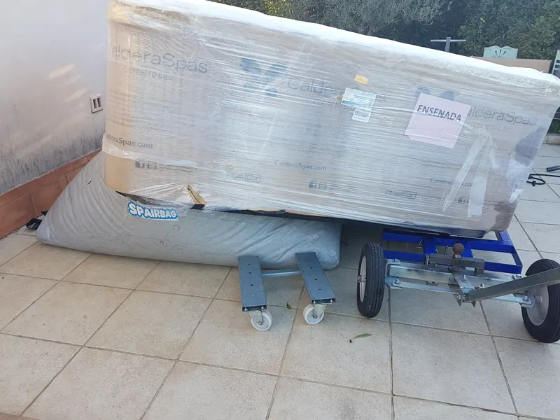 Spa Caldera Spas emballé, couché sur un coussin gonflable et un chariot, sur une terrasse carrelée