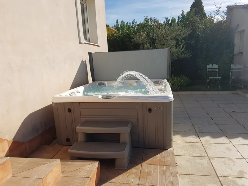 Spa rempli, fontaine en marche et marchepied, dans l'angle d'une terrasse à Caveirac