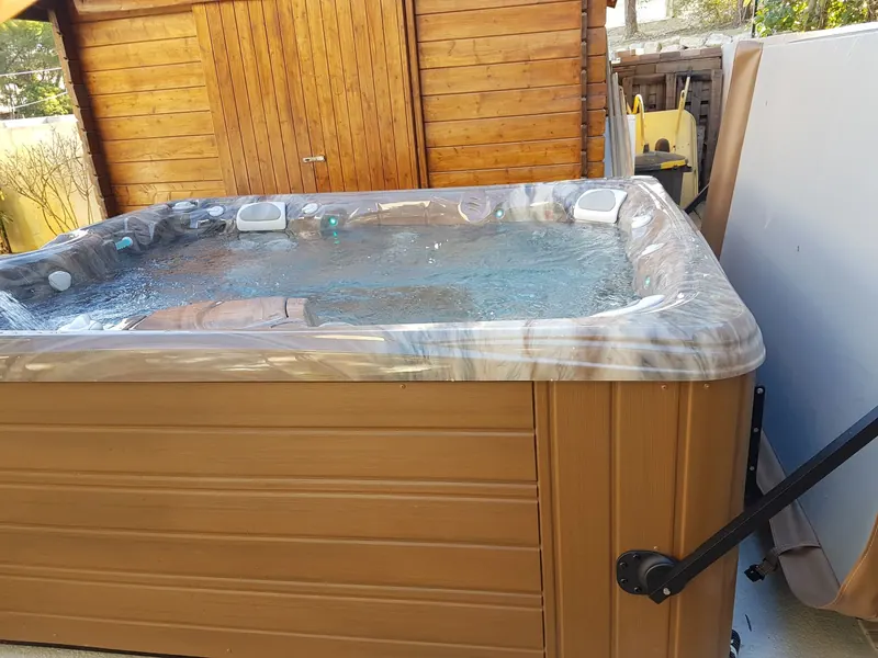 Spa rempli contre un abri en bois, lève-couverture fixé sur le côté, à Gigean