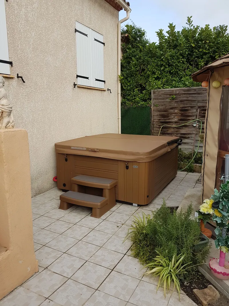 Vue de la terrasse avec le spa couvert, la haie et la tonnelle à Pignan