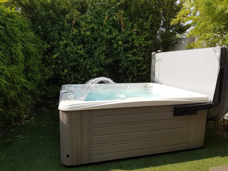 Spa Caldera Martinique en eau, fontaine en arc et couverture relevée, dans un jardin à Poussan