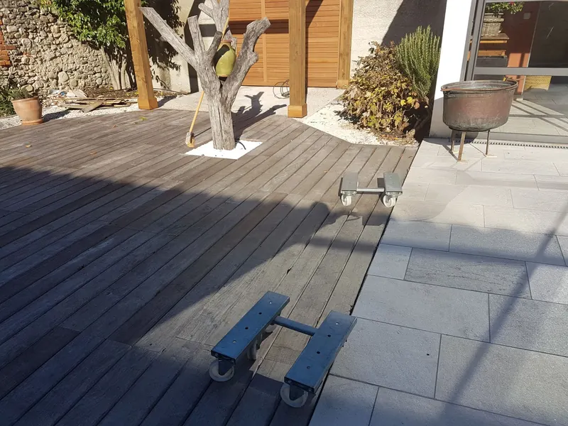 Deux chariots de manutention sur la terrasse en bois, devant la pergola encore vide