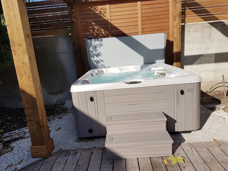 Spa blanc avec marchepied et jets en marche sous la pergola en bois
