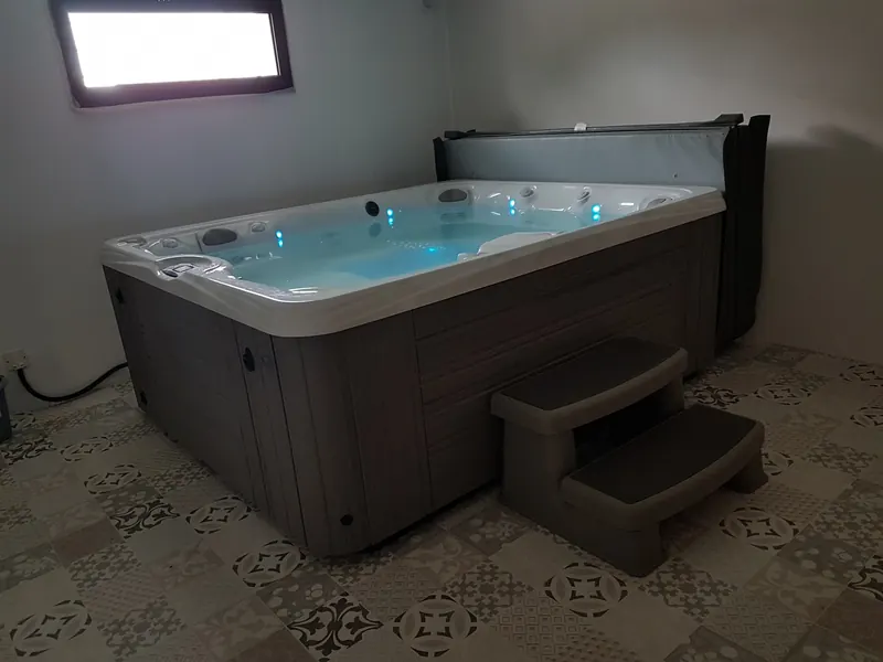 Spa Caldera Martinique éclairé en bleu, vu de biais sur un carrelage à motifs à Saint-Geniès-des-Mourgues