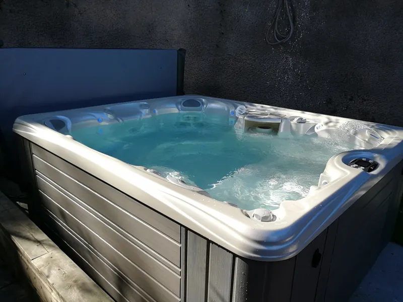 Spa Caldera rempli d'eau turquoise, buses en marche, contre un mur crépi à Sète