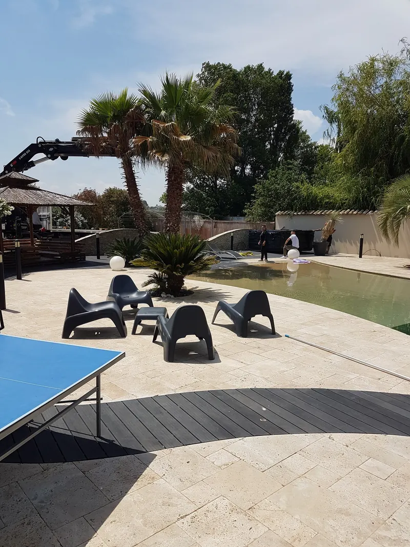 Spa encore emballé déposé au fond de la terrasse d'une piscine, bras de grue à gauche, à Mèze