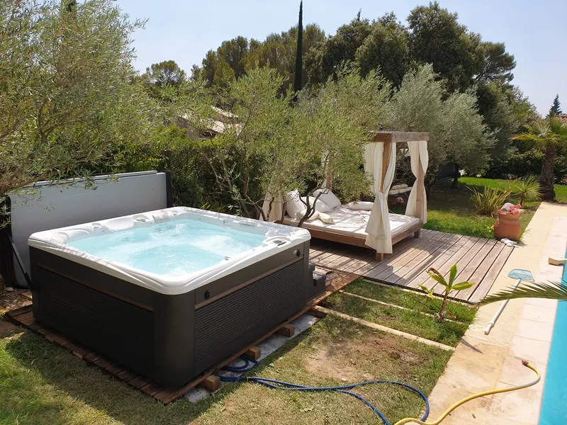 Spa installé entre oliviers, terrasse bois et piscine dans un jardin à Saint-Jean-de-Cuculles