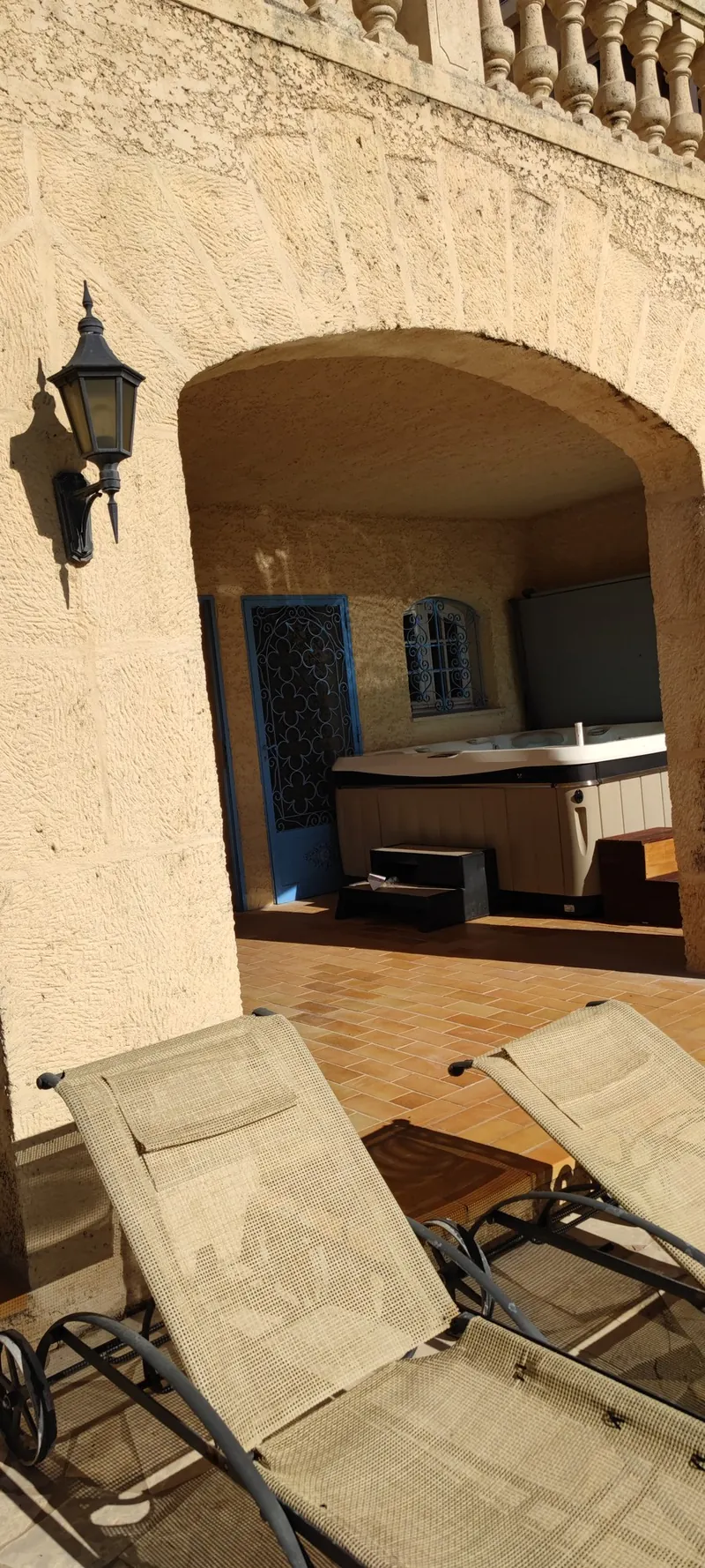 Spa en place sous l'arcade, couverture relevée, marches noires et transats devant