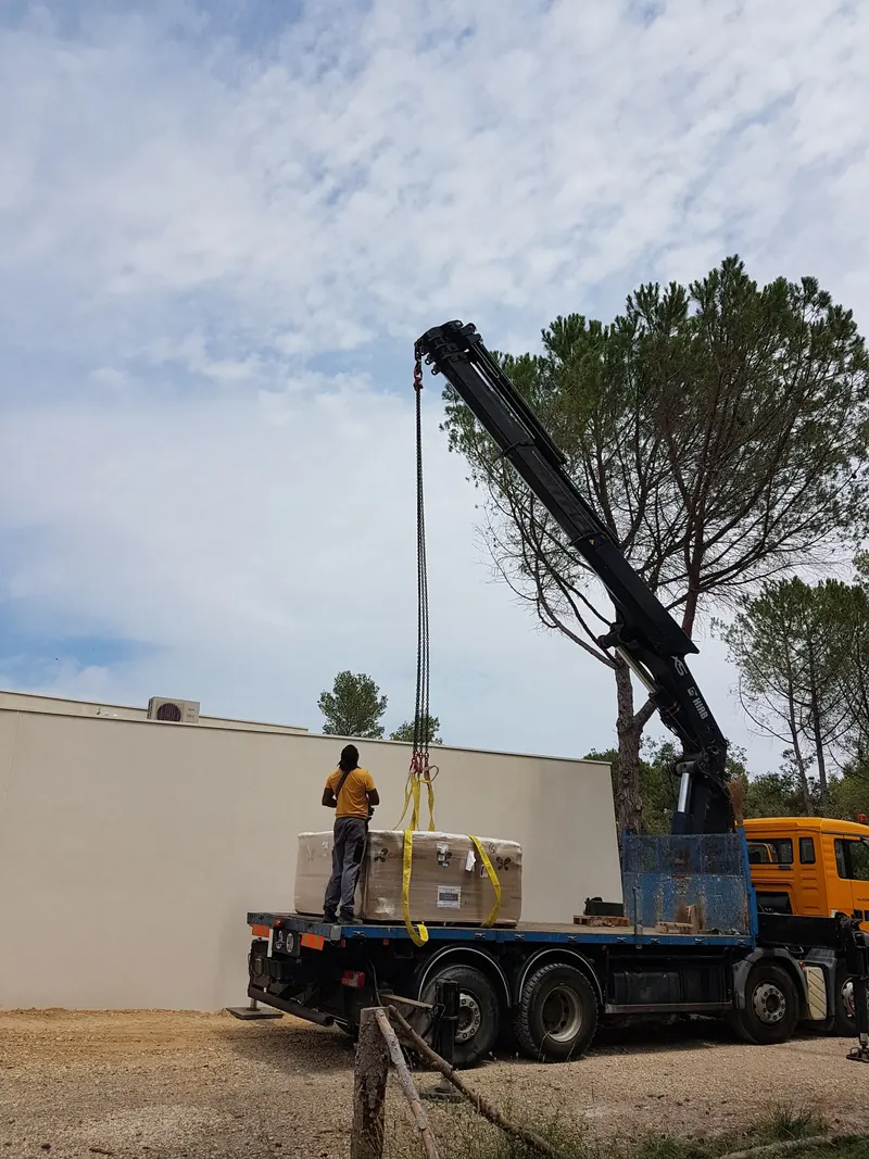 Spa Caldera emballé sur le plateau d'un camion-grue, devant un haut mur, à Langlade