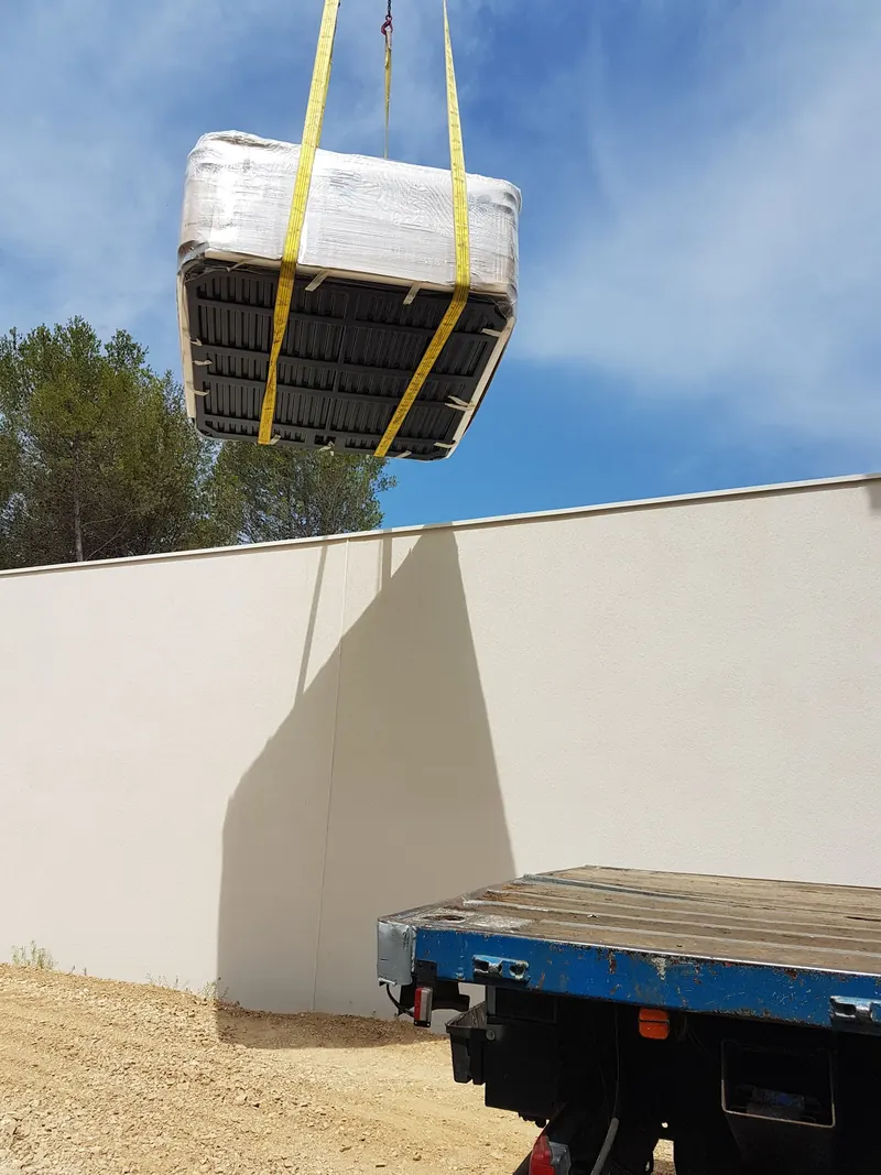 Spa emballé suspendu à la grue au-dessus d'un mur de clôture à Langlade