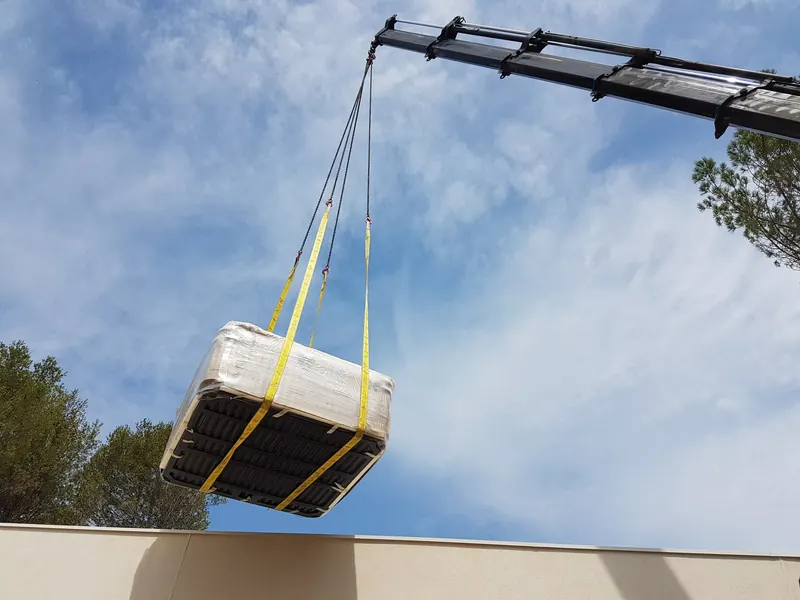 Spa sanglé au bras de la grue, vu d'en dessous, au-dessus du mur à Langlade