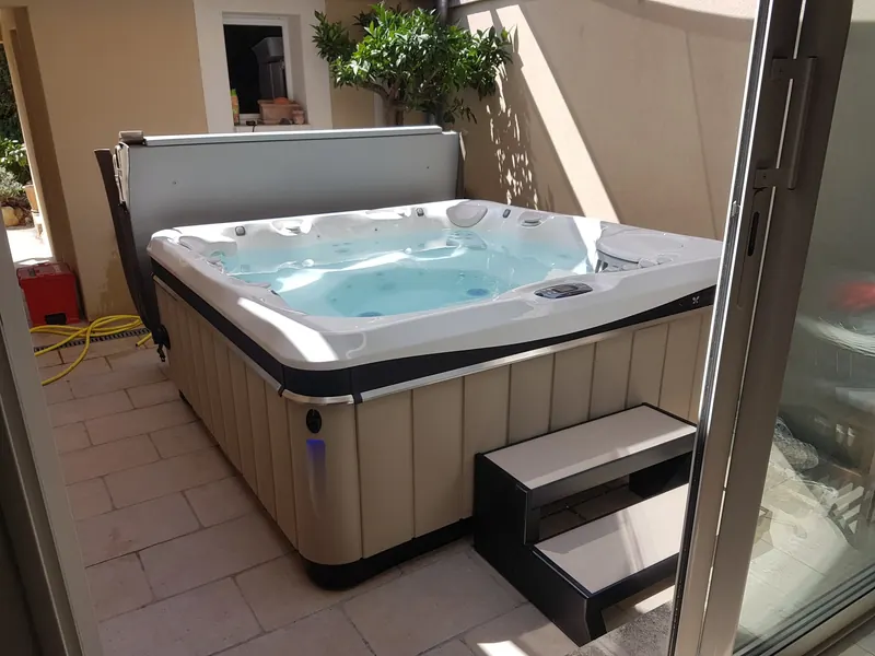 Spa Caldera Tahitian rempli dans un patio dallé, avec lève-couverture et marchepied, aux Angles
