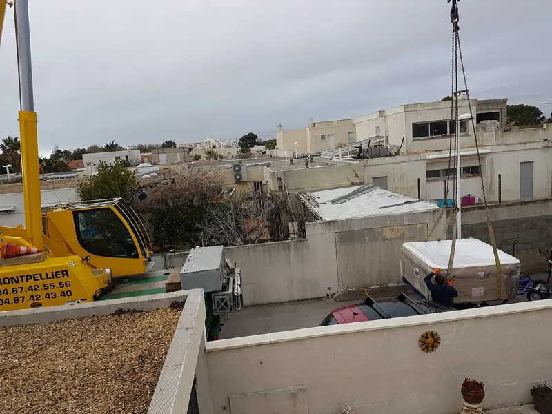 Grue jaune et spa emballé sanglé sur sa remorque dans la rue, avant le levage à Mauguio
