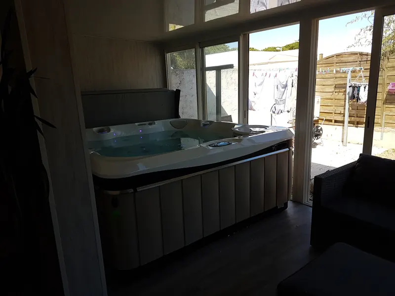 Spa installé dans une pièce aux grandes baies vitrées ouvertes sur le jardin à Mauguio