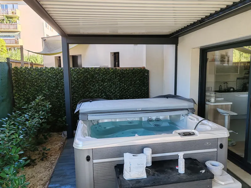 Spa blanc installé sous la pergola, avec sa couverture