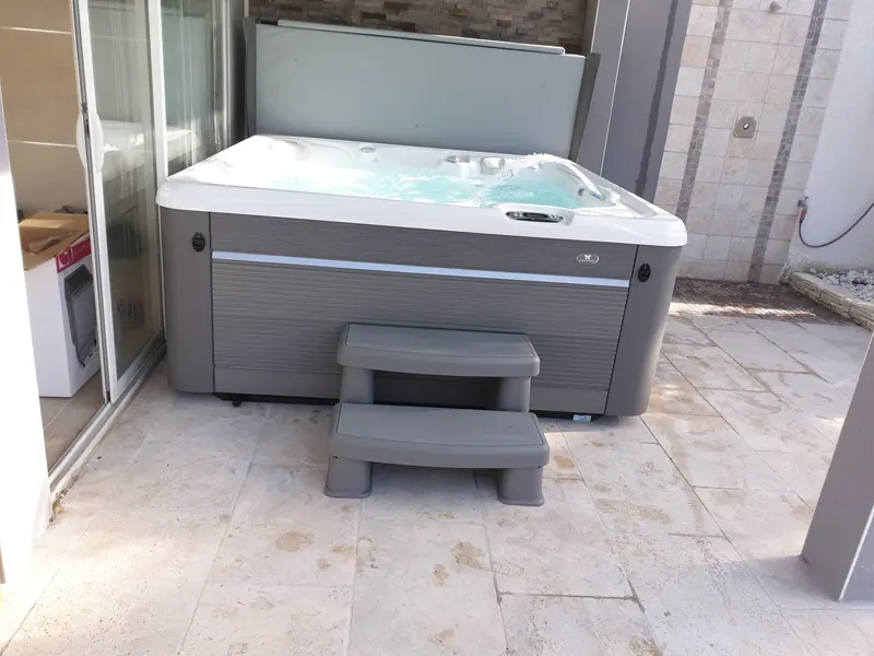 Spa gris sous une terrasse couverte, couverture relevée contre le mur et marchepied devant, à Vic-la-Gardiole