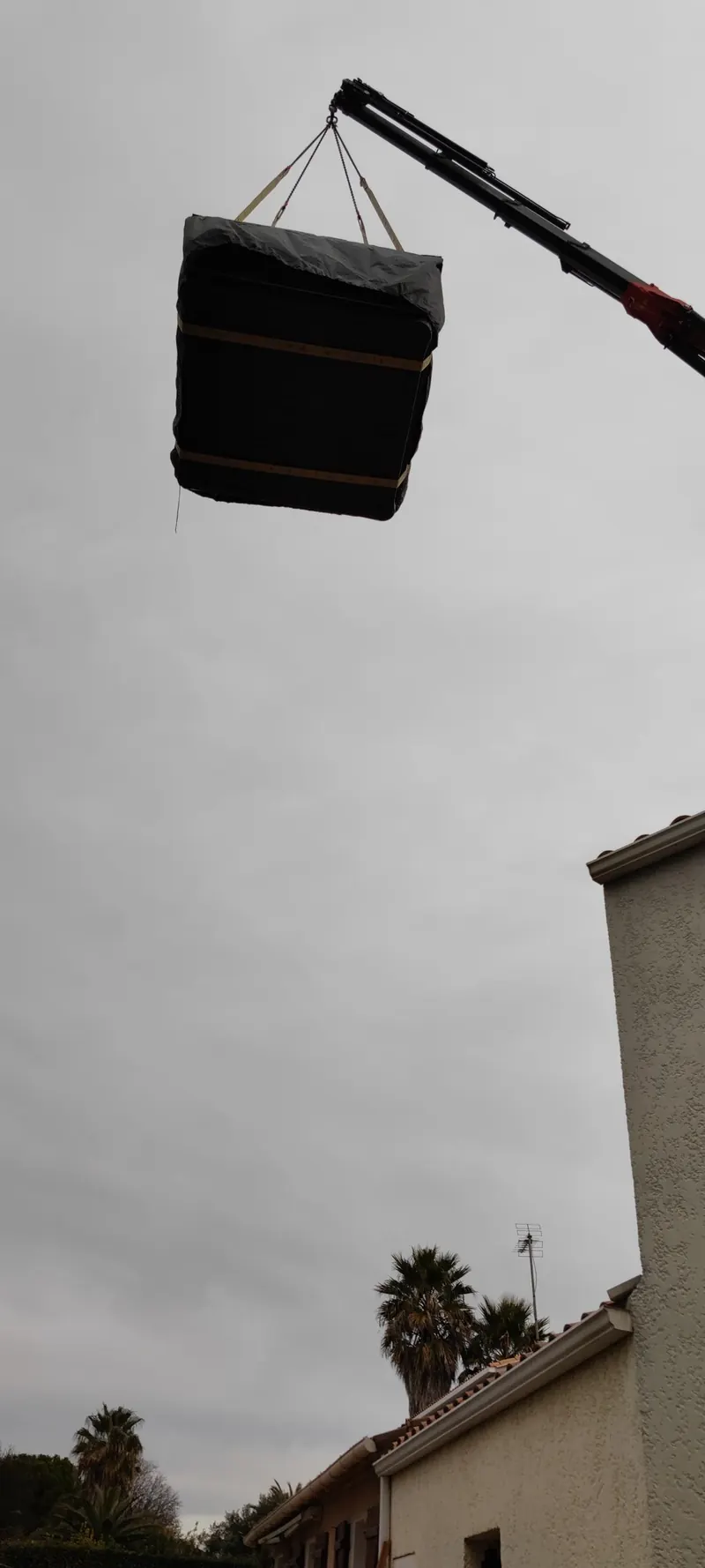 Spa suspendu à la grue au-dessus d'une ruelle étroite, entre deux murs de pierre