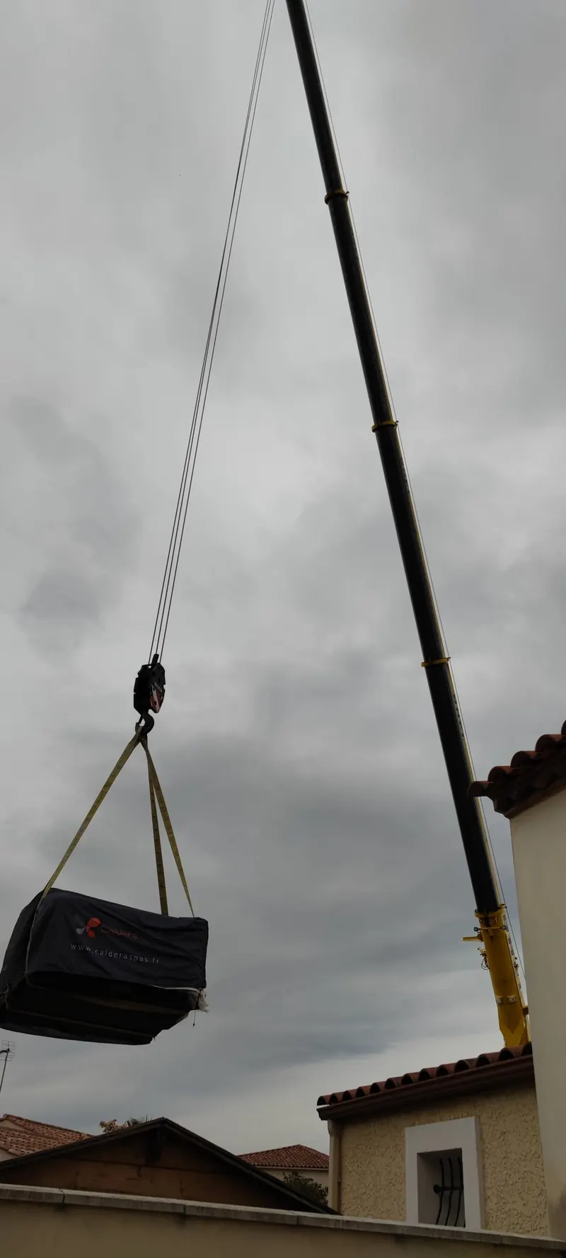 Spa noir suspendu à la grue, treuil en action