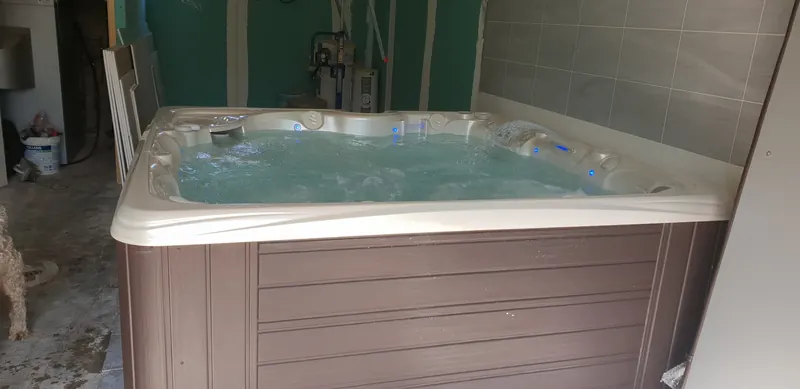 Spa en marche, jets et cascade allumés, dans une pièce intérieure en travaux à Canohès