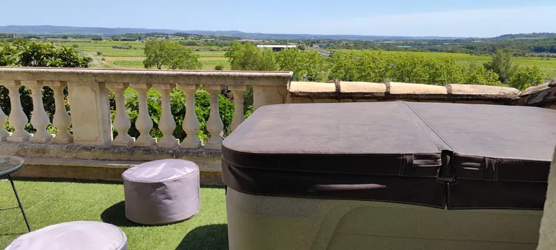 Spa fermé sous sa couverture brune, balustrade en pierre et plaine en arrière-plan