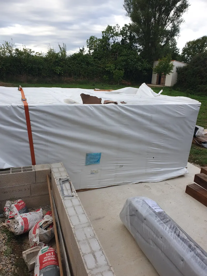 Spa de nage emballé déposé sur une dalle béton, à côté de murets en parpaings, à Narbonne