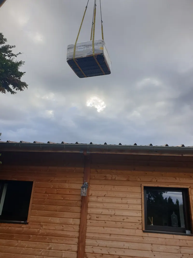 Spa emballé suspendu à la grue au-dessus du toit d'une maison en bois à Narbonne