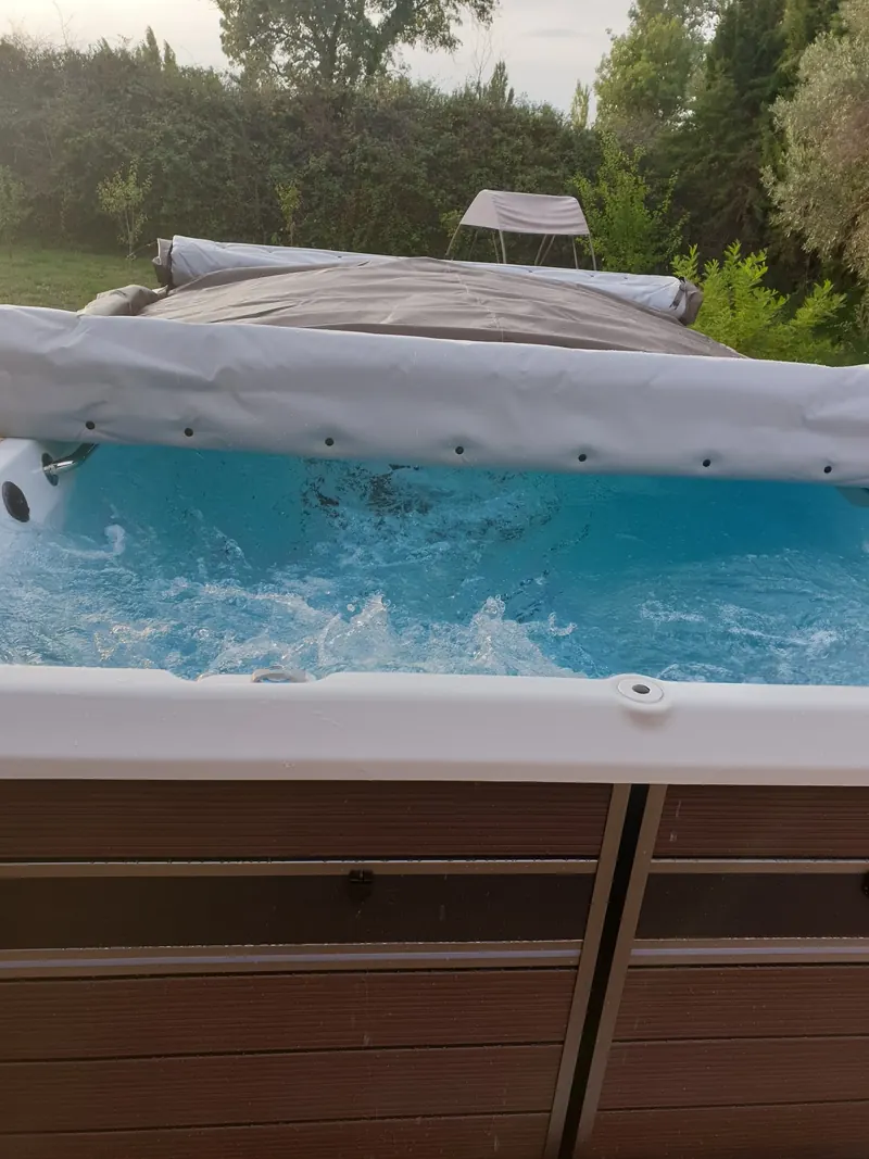 Spa de nage rempli, jets en marche, couverture roulée sur le côté, dans un jardin à Narbonne