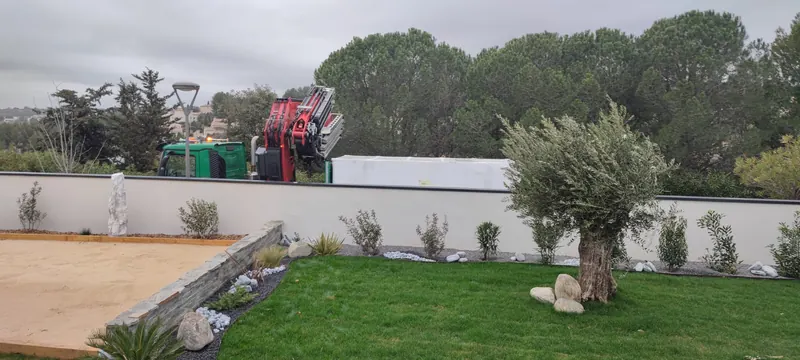 Grue levant le spa de nage enveloppé au-dessus du jardin, mur blanc et végétation au fond