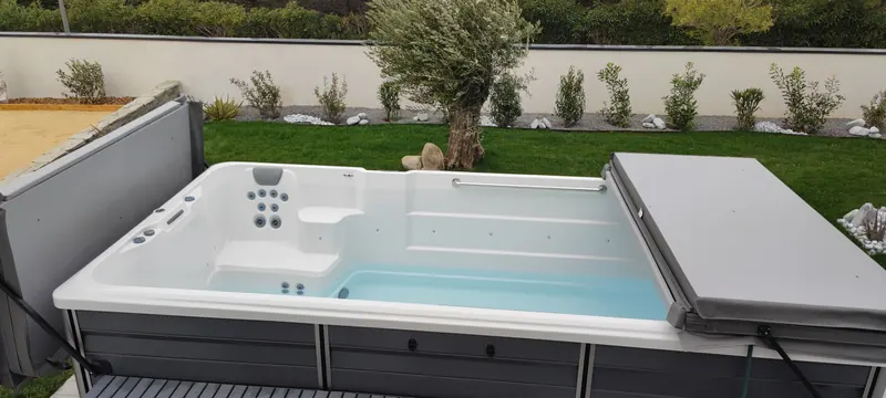 Spa de nage blanc rempli d'eau, vu de côté