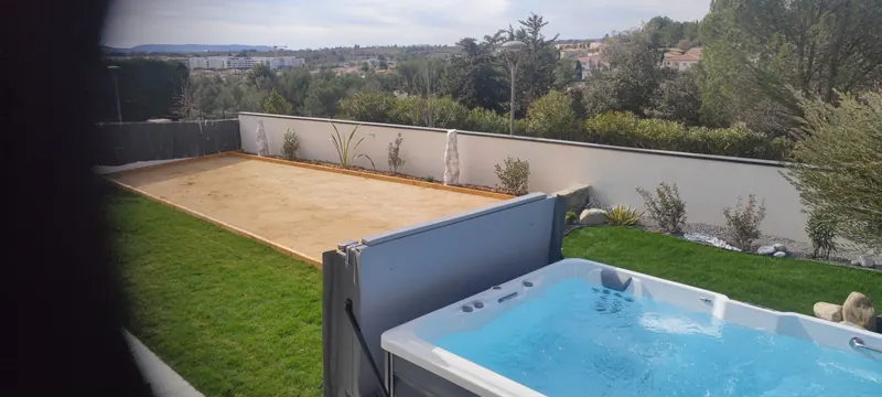 Spa de nage blanc rempli, avec le jardin et la végétation derrière
