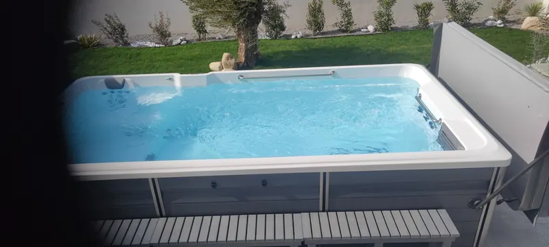 Spa de nage vide, avec sa structure blanche et son escalier d'accès