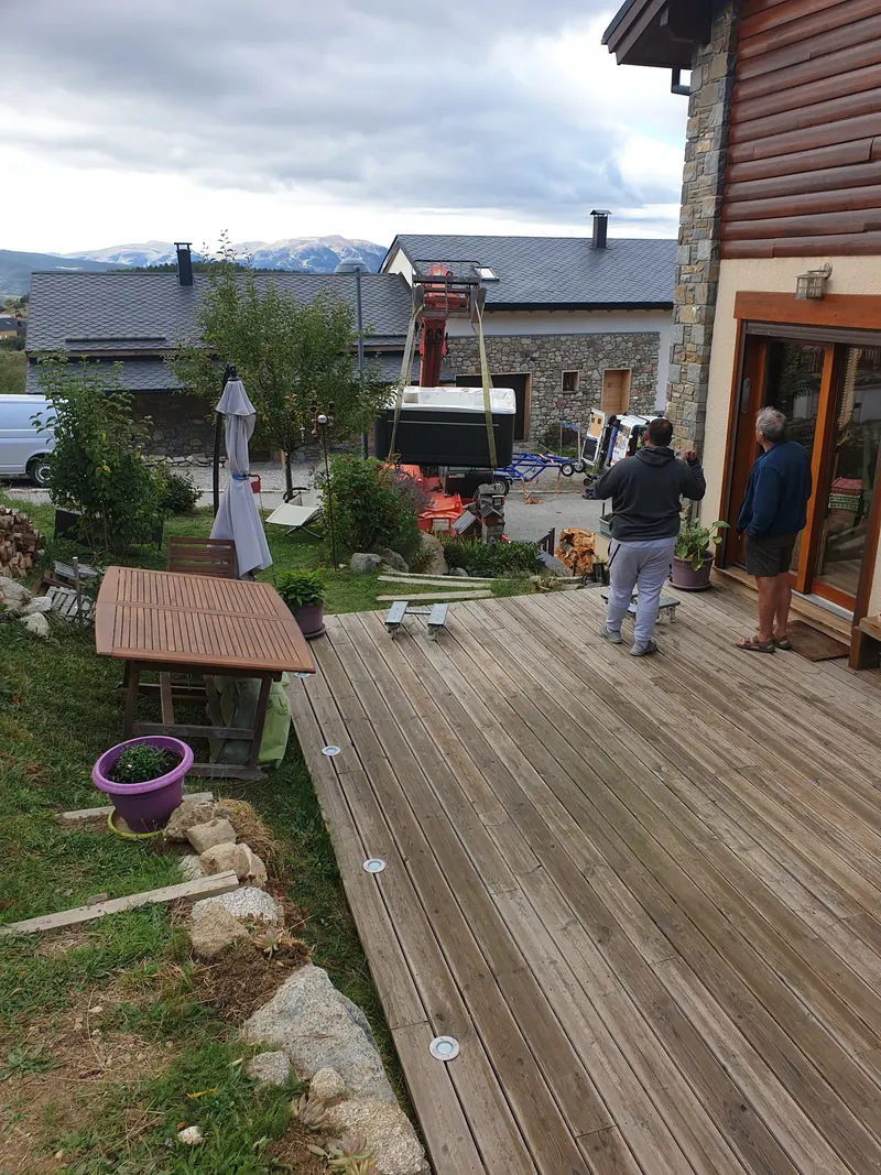Spa levé au-dessus du jardin, vu depuis la terrasse en bois où attendent les chariots, à Égat