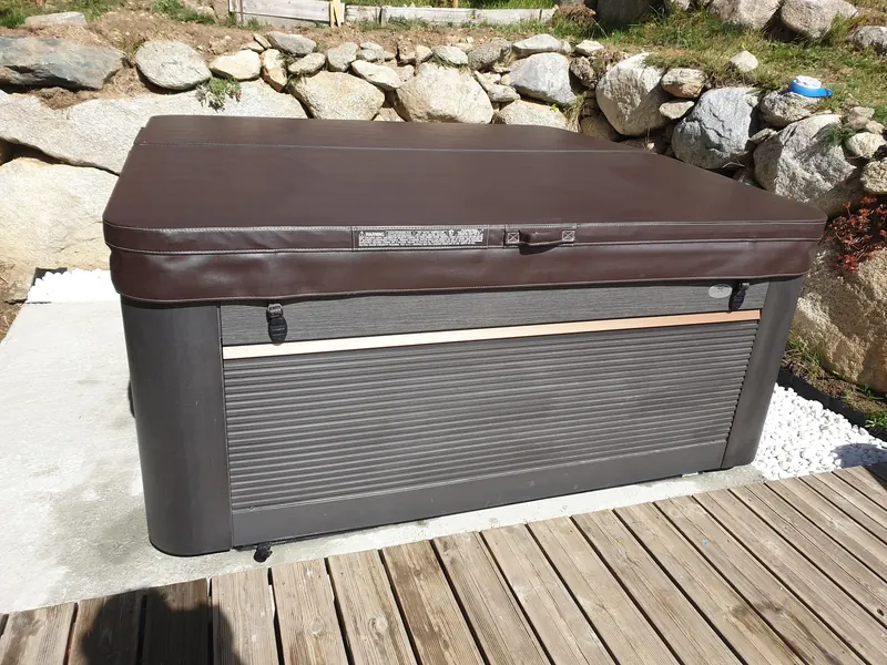 Habillage gris à liseré cuivré et couvercle marron du spa installé à Égat