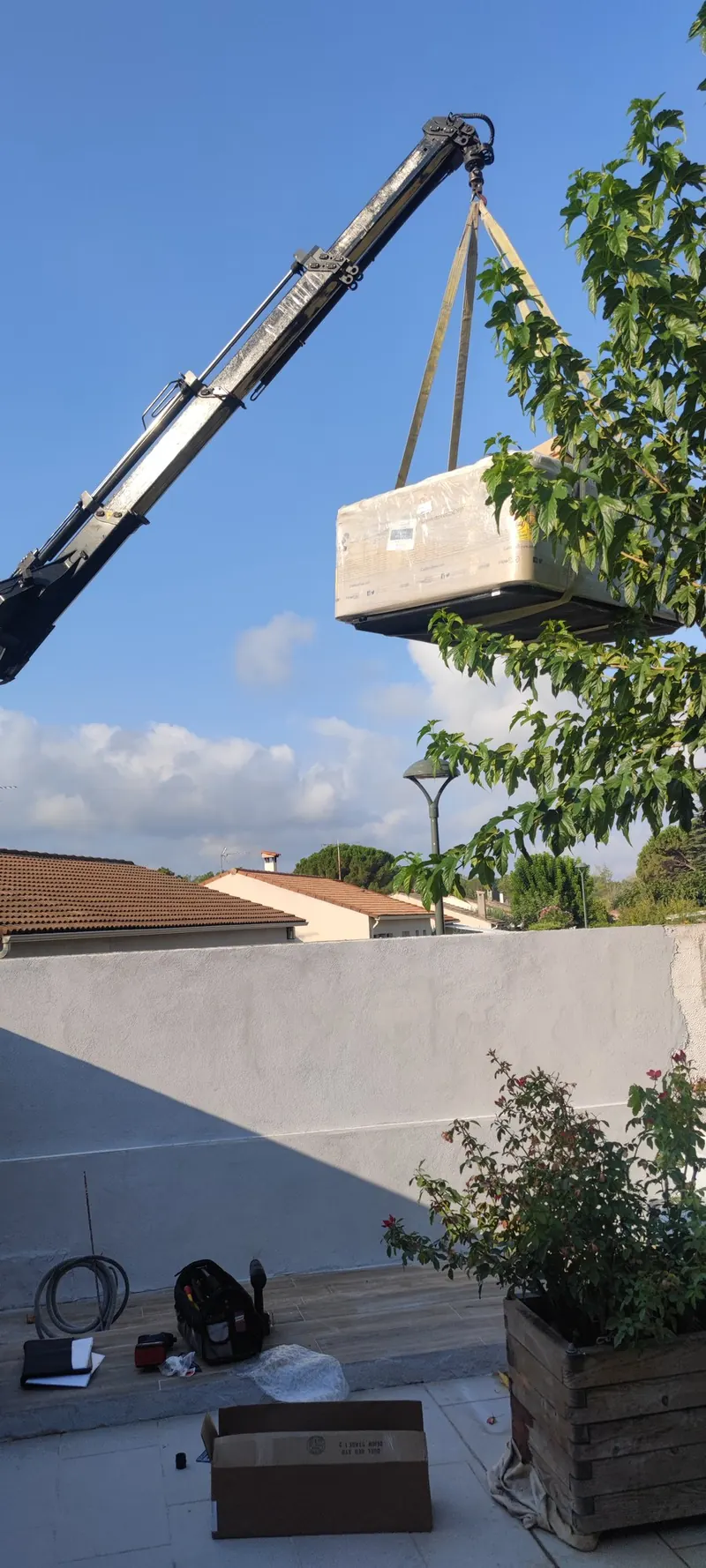 Spa suspendu à la grue par des haubans, avant la descente sur la toiture