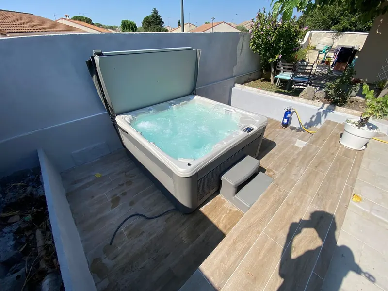Spa blanc sur la terrasse, entouré de vérins de levage et de protections