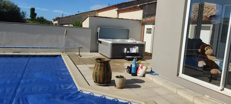 Terrasse dallée : le spa au fond, la piscine à bâche bleue au premier plan