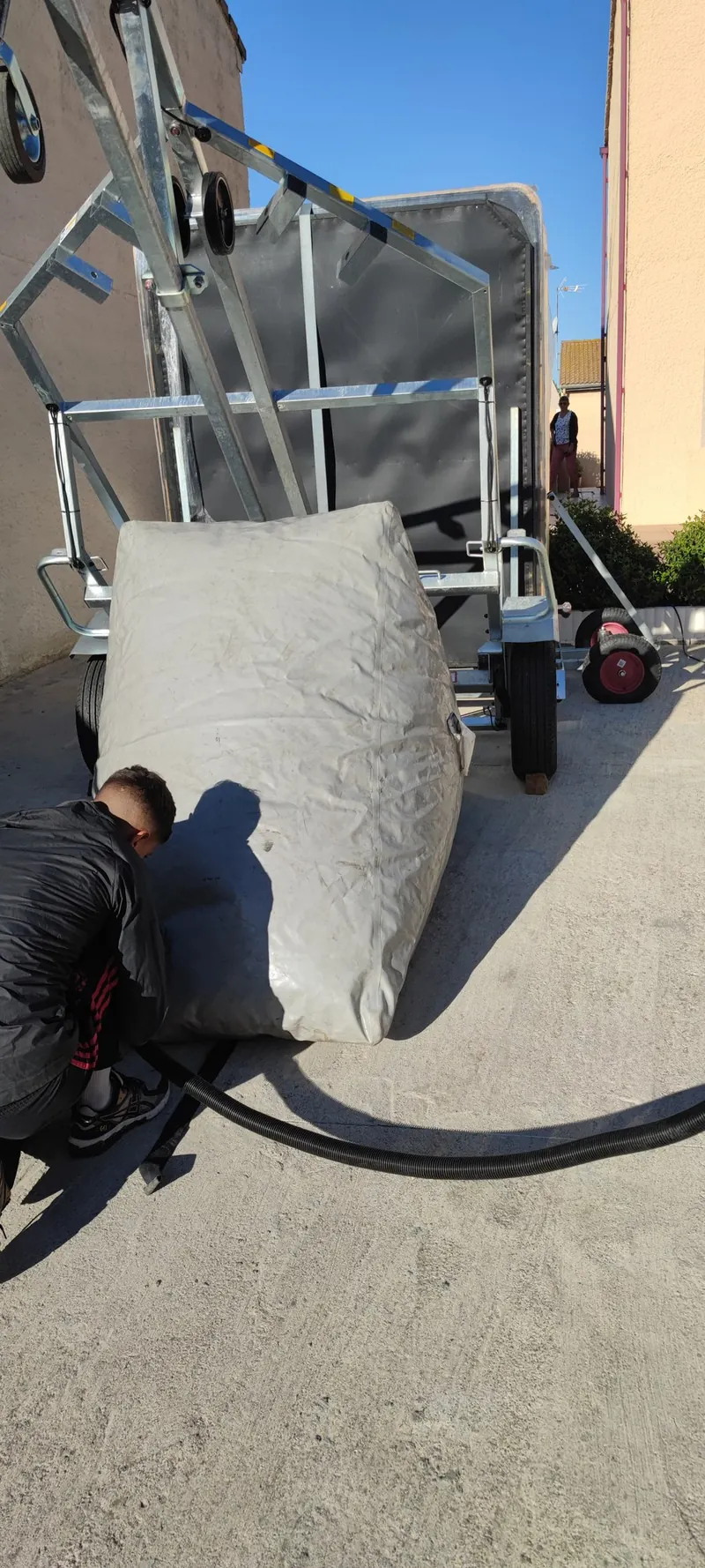 Spa debout sur un chariot de manutention galvanisé, personne accroupie près d'un coussin gris