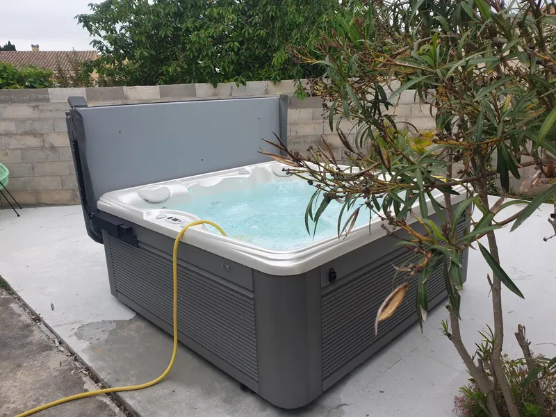 Vue de côté du spa blanc et gris sur la terrasse