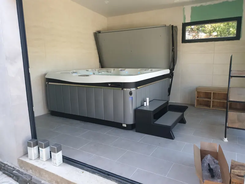 Vue de côté du spa en intérieur, avec ses marches d'accès