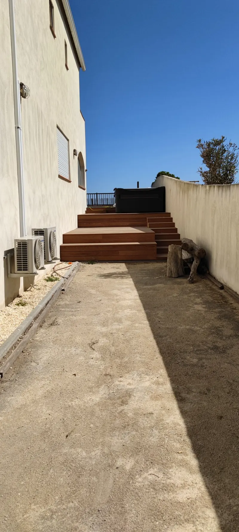 Spa encastré dans une terrasse en bois, avec escalier d'accès et murs de clôture