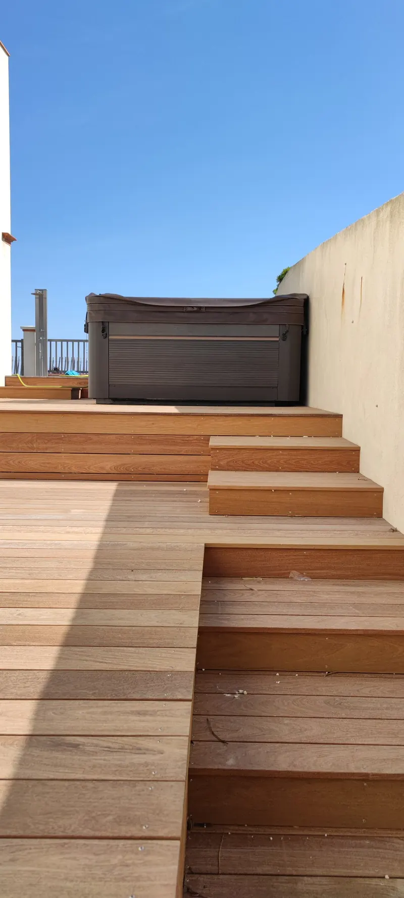 Plateforme surélevée en bois avec spa fermé et clôtures