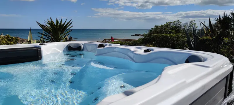 Spa en eau, assises et jets, mer à l'horizon derrière un yucca