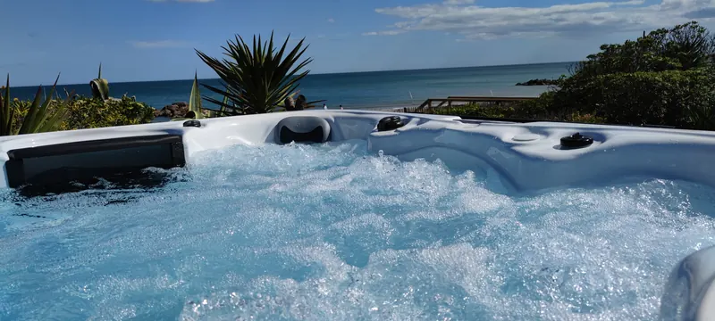 Eau agitée par les jets du spa, mer et végétation derrière