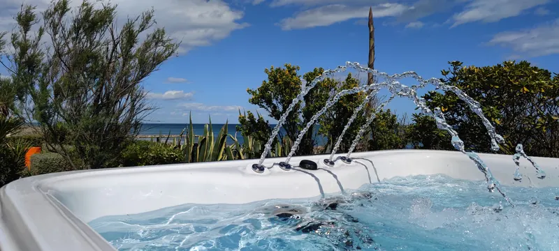 Jets d'eau en arcs retombant dans le spa, végétation et ciel