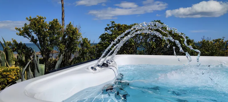 Arcs d'eau jaillissant du bord du spa, ciel bleu au-dessus