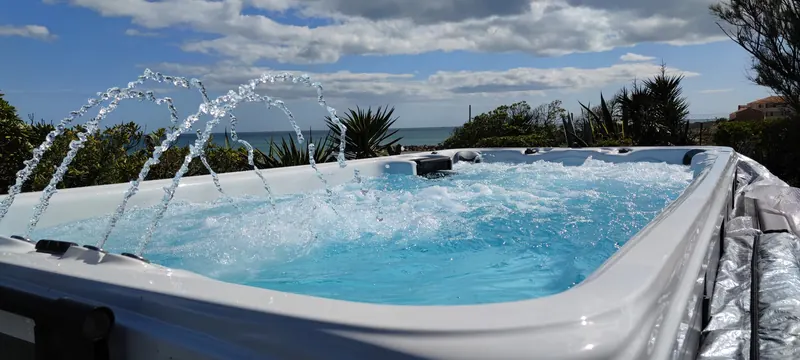 Arcs d'eau et eau agitée, mer et jetée en pierre derrière le spa