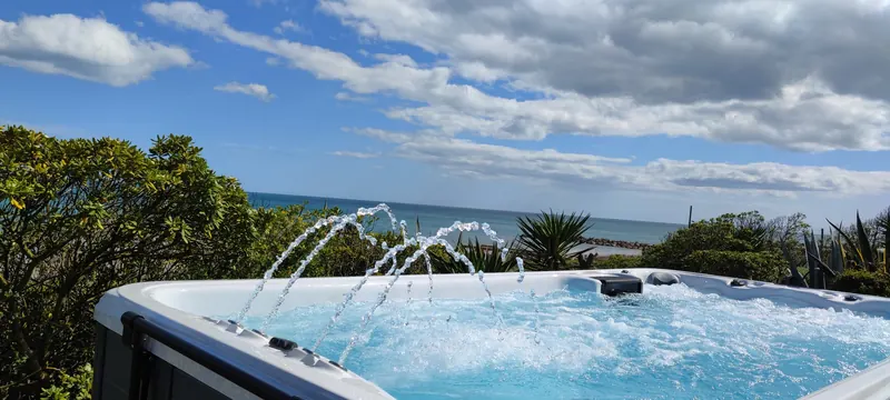Arcs d'eau retombant dans le spa, végétation et mer au fond