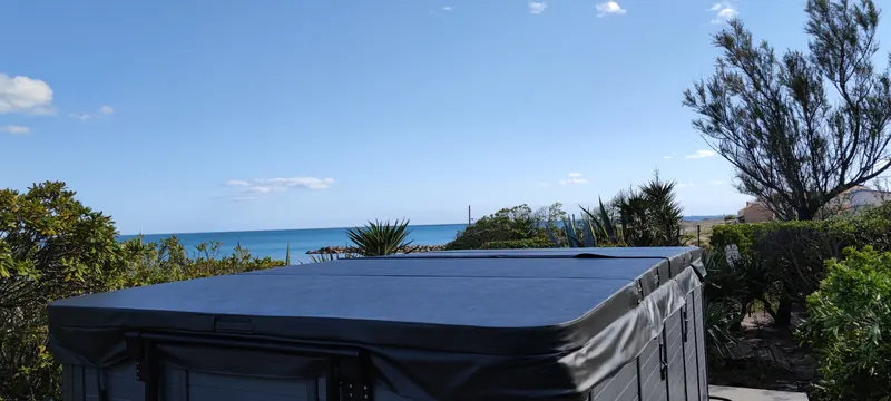 Spa fermé sous son couvercle sombre, mer au loin